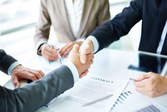 Handshake over a contract. Being hired is one of the key reasons why learning French is important.