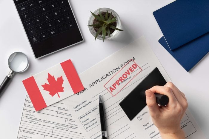 Approved visa application form next to a Canadian paper flag, one of the reasons why french is important