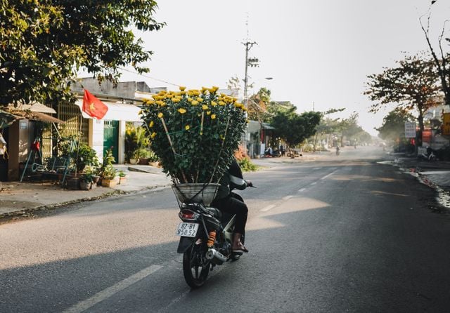 Motorcyclist carrying flowers in Thailand.