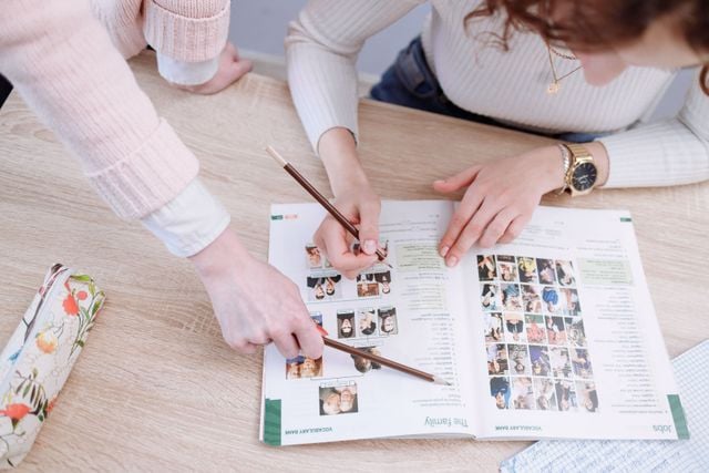 Language learners using a workbook together to practise vocabulary and develop effective study strategies.